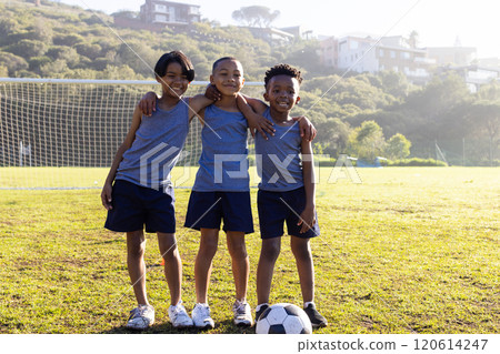 Outdoors, Playing soccer, three multiracial boys in sportswear smiling on school field 120614247