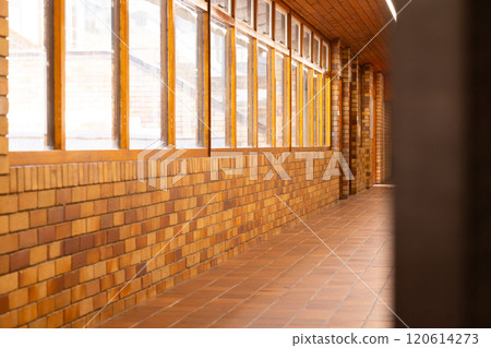 Empty school hallway with brick walls and large windows, bright and clean 120614273