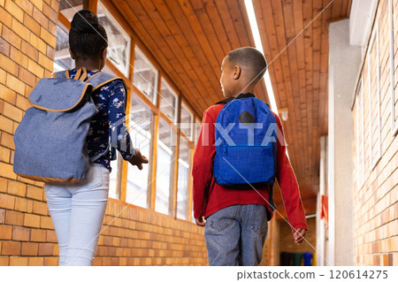 Walking in school hallway, two multiracial boy and girl with backpacks heading to classroom Walking in school hallway, two multiracial boy and girl with backpacks heading to classroom 120614275