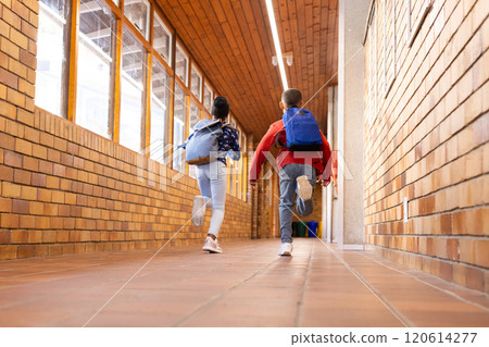 Running down school hallway, multiracial boy and girl with backpacks heading to classroom Running down school hallway, multiracial boy and girl with backpacks heading to classroom 120614277