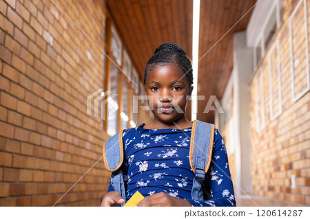 In school, african american girl with backpack standing in hallway, looking at camera 120614287