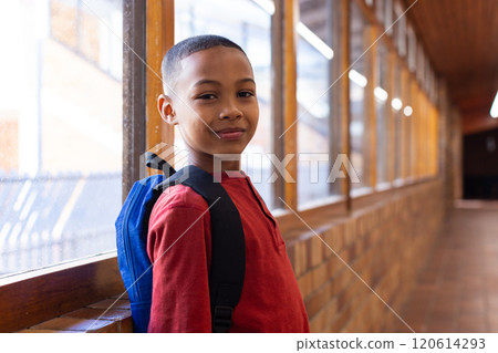 Smiling boy with backpack standing in school hallway, looking at camera Smiling boy with backpack standing in school hallway, looking at camera 120614293