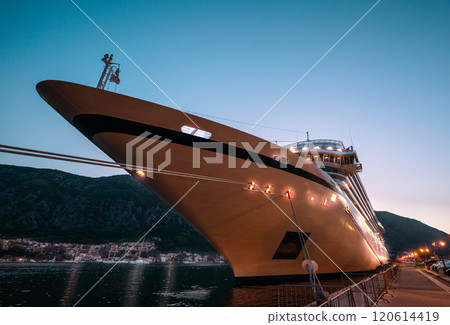 An elegant cruise liner docked at twilight, its lights shimmering against the evening sky, embodying the allure of ocean voyages. 120614419