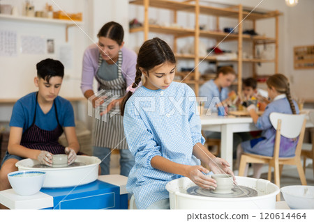Children working at potter's wheel with teacher in art studio Children working at potter's wheel with teacher in art studio 120614464