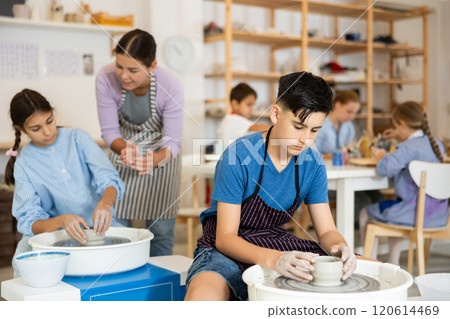 Children working at potter's wheel with teacher in art studio Children working at potter's wheel with teacher in art studio 120614469