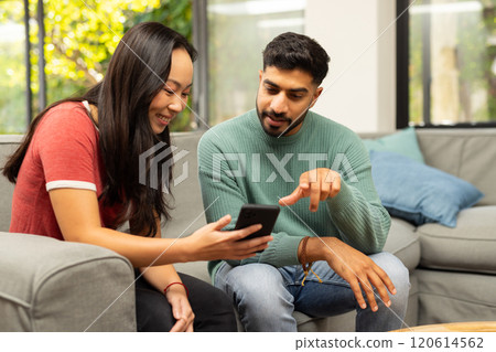Looking at smartphone, young diverse friends sitting on couch and smiling together 120614562