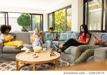 diverse friends sitting on couch using smartphones and relaxing in living room, copy space diverse friends sitting on couch using smartphones and relaxing in living room, copy space 120614574