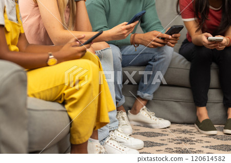 Using smartphones, group of young friends sitting together on couch Using smartphones, group of young friends sitting together on couch 120614582