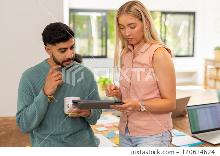 Discussing project, young friends using tablet and holding coffee cup in office, start up business Discussing project, young friends using tablet and holding coffee cup in office, start up business 120614624