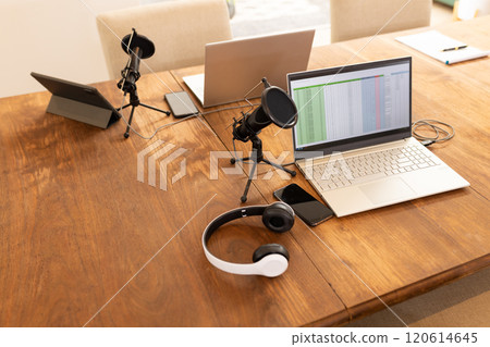 Podcasting setup with laptops, microphones, and headphones on wooden table, copy space 120614645