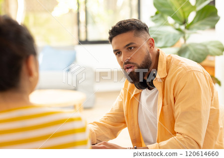 Wearing headphones and yellow shirt, man engaging in conversation with friend Wearing headphones and yellow shirt, man engaging in conversation with friend 120614660