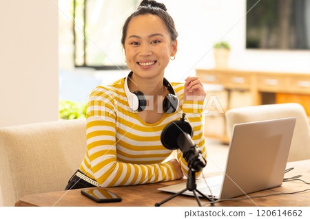 Smiling woman with headphones recording podcast using laptop and microphone Smiling woman with headphones recording podcast using laptop and microphone 120614662