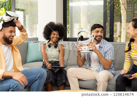 Friends sitting on couch, holding VR headsets, enjoying technology together 120614674