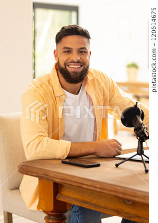 Smiling man sitting at table with microphone and smartphone, ready for podcast Smiling man sitting at table with microphone and smartphone, ready for podcast 120614675