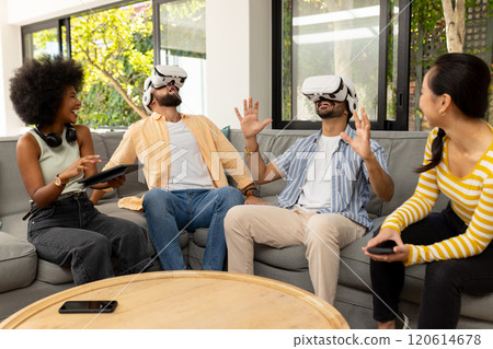 Using VR headsets, diverse friends enjoying virtual reality experience together indoors 120614678
