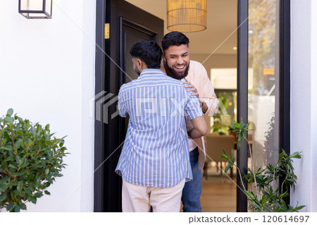 Greeting friend at door, man smiling and hugging visitor warmly 120614697