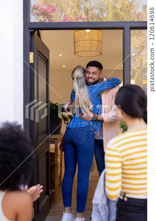 Welcoming friends, man hugging woman at front door, others arriving Welcoming friends, man hugging woman at front door, others arriving 120614698