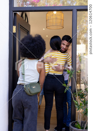 Welcoming friends at door, man hugging woman while another friend arrives Welcoming friends at door, man hugging woman while another friend arrives 120614700