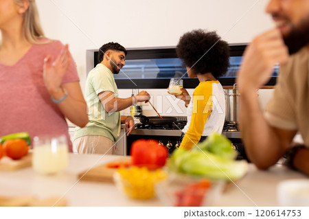 Preparing meal together, diverse friends cooking in kitchen, enjoying fresh ingredients Preparing meal together, diverse friends cooking in kitchen, enjoying fresh ingredients 120614753