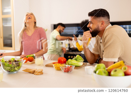Friends preparing meal together in kitchen, laughing and enjoying cooking Friends preparing meal together in kitchen, laughing and enjoying cooking 120614760