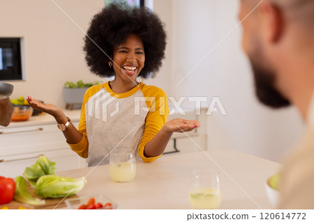 Laughing and enjoying conversation, diverse friends sitting at kitchen table with drinks Laughing and enjoying conversation, diverse friends sitting at kitchen table with drinks 120614772