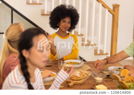 Eating lunch together, group of young diverse friends enjoying meal at table 120614800
