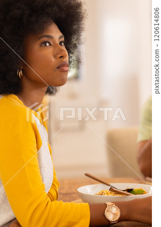 Eating meal, woman in yellow shirt looking thoughtfully away from table, copy space 120614806