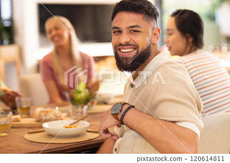 Smiling man enjoying meal with diverse friends at dining table, having good time 120614811