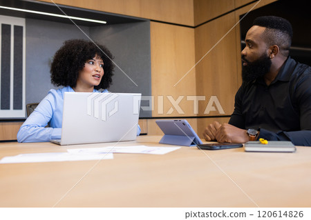 Discussing project, colleagues using laptop and tablet in modern office meeting 120614826