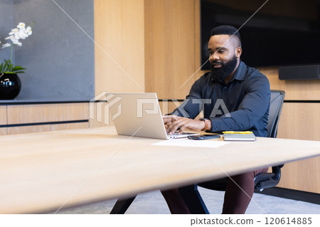 Working on laptop, african american businessman typing at desk in modern office setting, copy space Working on laptop, african american businessman typing at desk in modern office setting, copy space 120614885