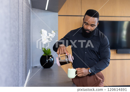 Pouring coffee into mug, african american businessman taking break in modern office kitchen 120614891