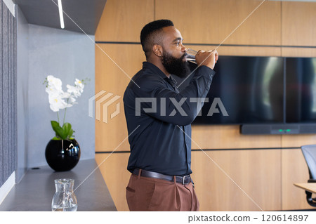 Drinking water, african american businessman taking break in modern office conference room 120614897