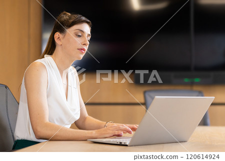 Working on laptop, businesswoman focusing on tasks in modern office setting, copy space Working on laptop, businesswoman focusing on tasks in modern office setting, copy space 120614924
