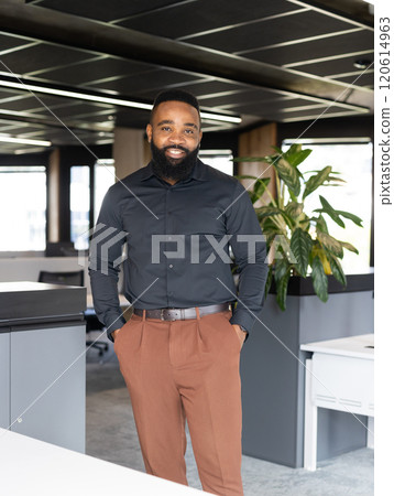 Smiling African American businessman in modern office, standing with hands in pockets Smiling African American businessman in modern office, standing with hands in pockets 120614963