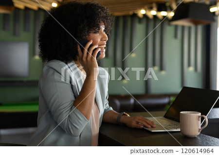 Talking on smartphone, woman using laptop and drinking coffee in modern office Talking on smartphone, woman using laptop and drinking coffee in modern office 120614964