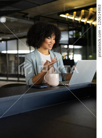 Working on laptop, businesswoman in office having video call with coffee mug nearby Working on laptop, businesswoman in office having video call with coffee mug nearby 120614968