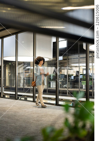 Walking in modern office, woman holding laptop and wearing business attire Walking in modern office, woman holding laptop and wearing business attire 120615006