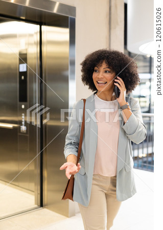 Talking on smartphone, businesswoman walking near elevator in office building Talking on smartphone, businesswoman walking near elevator in office building 120615026