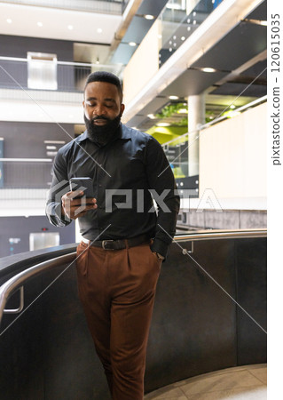 Using smartphone, man in business attire standing in modern office building Using smartphone, man in business attire standing in modern office building 120615035