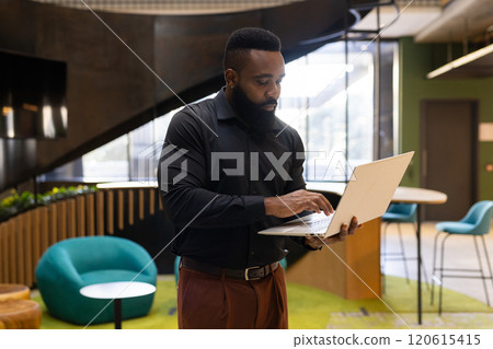 Using laptop, businessman working in modern office environment, focusing on tasks 120615415