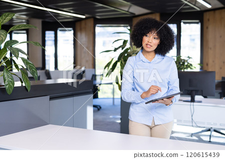 Businesswoman using tablet and standing in modern office, focusing on work, copy space Businesswoman using tablet and standing in modern office, focusing on work, copy space 120615439