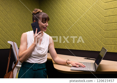 Using smartphone and laptop, businesswoman multitasking in modern office workspace Using smartphone and laptop, businesswoman multitasking in modern office workspace 120615457