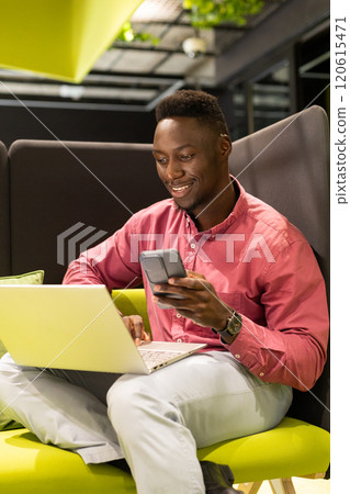 Using smartphone and laptop, african american man working in modern office environment Using smartphone and laptop, african american man working in modern office environment 120615471