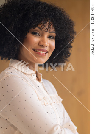 Smiling businesswoman in polka dot blouse posing confidently in office setting 120615493