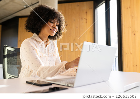 Working on laptop, woman smiling and using smartphone in modern office Working on laptop, woman smiling and using smartphone in modern office 120615502