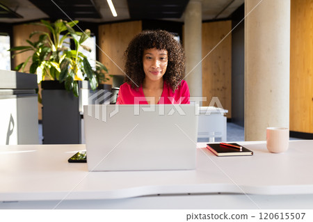 Working in modern office, woman using laptop with notebook and coffee mug nearby Working in modern office, woman using laptop with notebook and coffee mug nearby 120615507