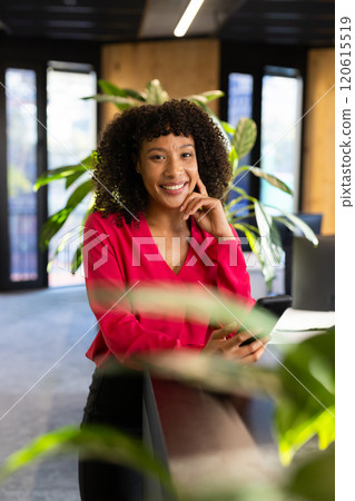 Smiling businesswoman holding smartphone, leaning on desk in modern office Smiling businesswoman holding smartphone, leaning on desk in modern office 120615519