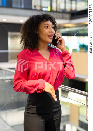 Talking on smartphone, businesswoman in red blouse standing in modern office Talking on smartphone, businesswoman in red blouse standing in modern office 120615528
