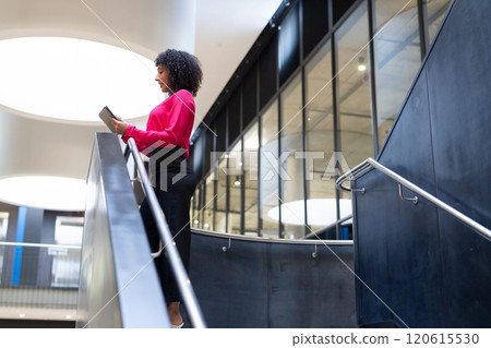 Businesswoman using tablet while standing on stairs in modern office building, copy space Businesswoman using tablet while standing on stairs in modern office building, copy space 120615530
