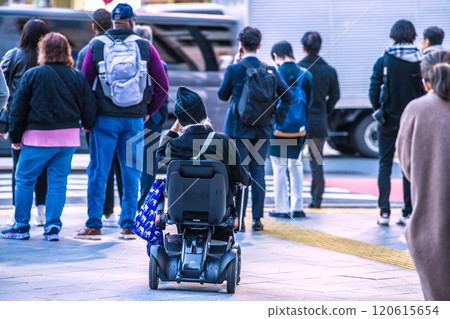 日本東京的城市景觀在城市的人群中...老齡化社會...一位坐在下一代電動輪椅上的老年婦女=東京(澀谷站前) 日本東京的城市景觀在城市的人群中...老齡化社會...一位坐在下一代電動輪椅上的老年婦女=東京(澀谷站前) 120615654